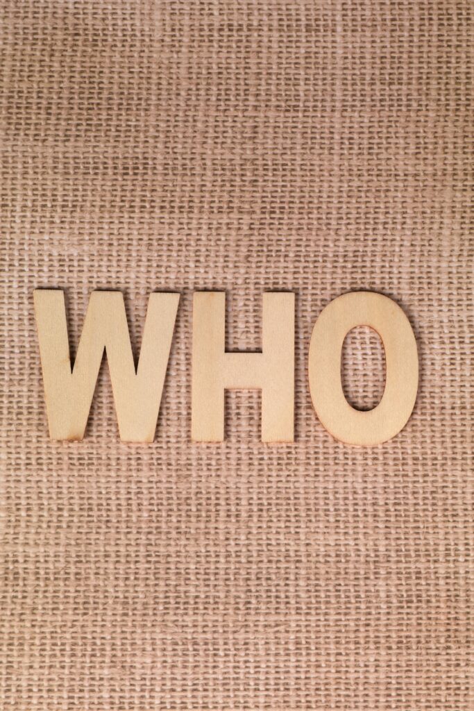 Wooden letters spelling WHO on a burlap fabric background.